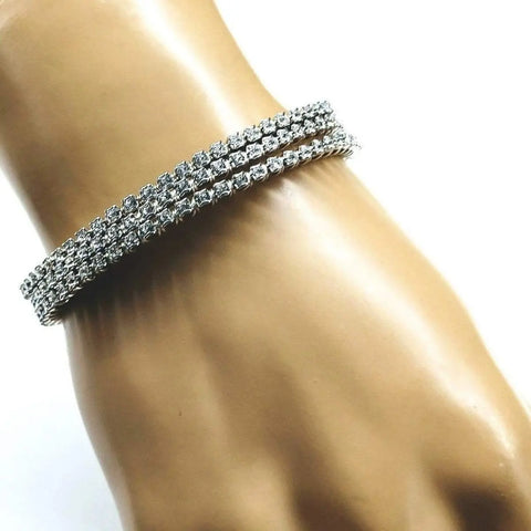 A hand wears the Alexa Martha Designs Wire Wrapped Crystal Rhinestone Tennis Bracelet Bangle, a double-row of clear sparkling stones, shown against a plain white background.