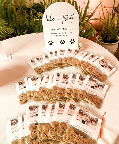 Personalized Cookies from Dogtown Bakery, shaped like hearts and made with pet-safe ingredients, are packaged in clear bags labeled “WE DO 09.15” and displayed with a sign: “Take a treat. Fur my friends who couldn’t make it to the party.”.