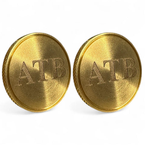 Fairway Reserve Personalized Ball Markers (Set of 2) feature gold-colored, round designs with ATB engraved, shown standing upright against a white background.