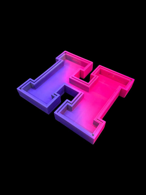 The B. James Design & Woodwork Letter Piggy Banks feature a 3D letter H tray with a purple-to-pink gradient on a black background—ideal for personalized savings or as a stylish decor accent.