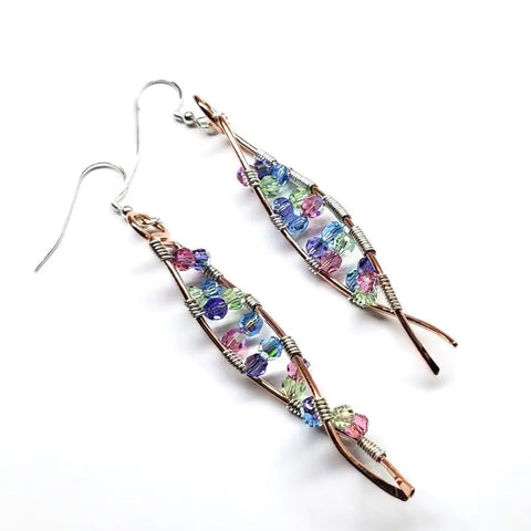 The DNA Strand Double Helix Long Crystal Earrings by Alexa Martha Designs feature twisted copper wire and multicolored faceted blue, pink, green, and purple beads, elegantly displayed on a white background.