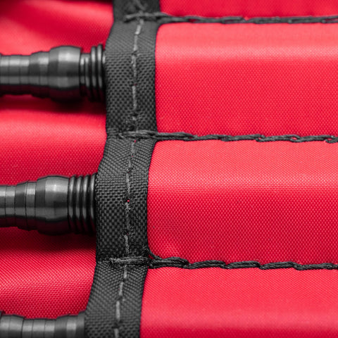 Close-up of black cylindrical tools by Hammerless Impact Technology, neatly organized in individual slots inside a red fabric pouch, part of the Deluxe Woodworking Kit.