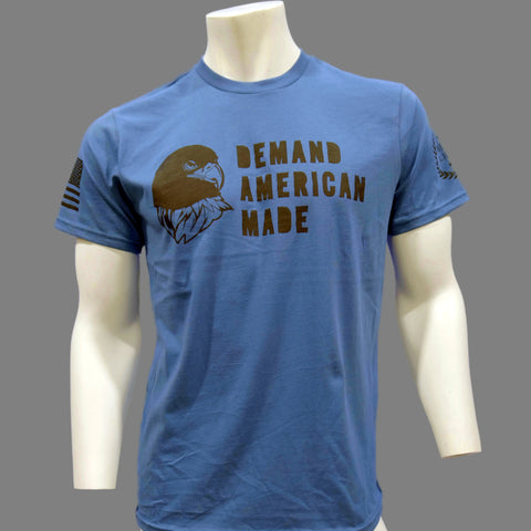 The American Lictor T-Shirt: Demand American Made features a blue eagle head graphic and slogan on the chest, with flag accents on gray sleeves. Check our Size Guide for your perfect fit.
