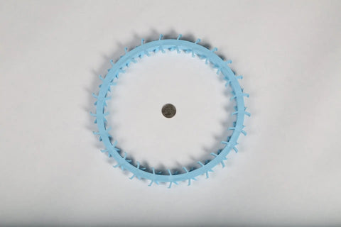 The Dentapup Dog Dental Toy - Blue by Dentapup is a circular plastic dog toy with evenly spaced protrusions, shown encircling a coin at the center on a plain white background.