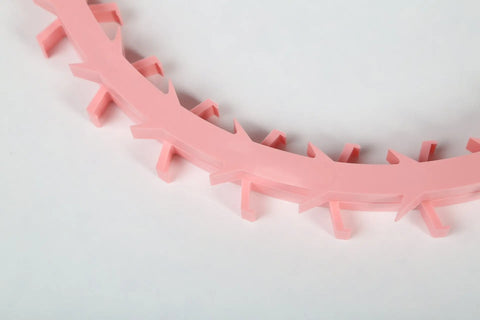 A close-up of the Dentapup Dog Dental Toy in pink by Dentapup, featuring a curved design with evenly spaced hooks to help remove plaque and tartar, set against a plain white background.