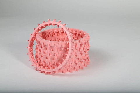 A stack of five Dentapup Dog Dental Toy - Pink by Dentapup, featuring circular shapes with rectangular protrusions for plaque and tartar removal, is set against a plain gray background. One ring leans against the stack.