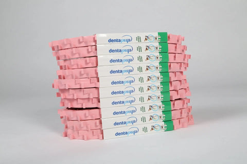 A stack of boxed Dentapup Dog Dental Toy - Pink by Dentapup is arranged in two neat rows, featuring a white and green design with pink edges, set against a plain white background.
