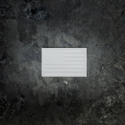 A Proudly USA Tattered American Flag Sticker (White and Clear, 2.68 x 1.71) is centered on a dark, textured surface.