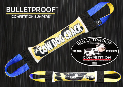 A yellow and black Dock Diving Bumper Tug - Competition Series Weighted - Cow Dog Crack by Bulletproof Pet Products Inc, with blue handles and COW DOG CRACK written on it, sits beside an oval BULLETPROOF TO THE MOOON logo with a cartoon cow and 14/16.
