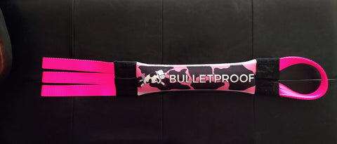 The Dock Diving Bumper Tug – Competition Series Weighted by Bulletproof Pet Products Inc, featuring a pink and black camo BULLETPROOF wrist strap with three pink loops, is shown as a durable dog tug toy on a black surface.