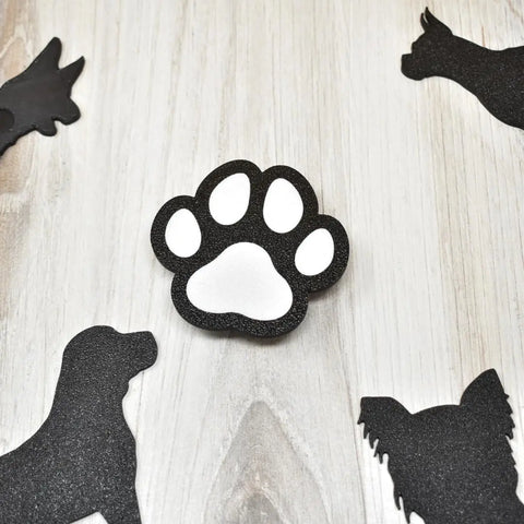 The Chatelet Manufacturing FRESHe BAGLETS Dog Paw Charm features a black and white paw print design, perfect for decorating Bogg Bags, Simply Southern, and other tote bags. Made in the USA—a cute accessory for any pet lover!.