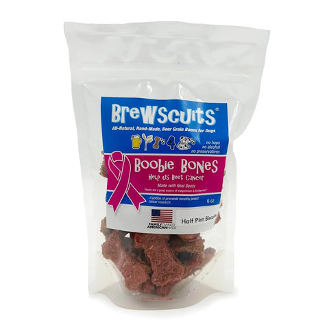 A clear resealable bag labeled Brewscuits shows Boobie Bones, USA-made all-natural dog treats. The packaging features a pink ribbon for breast cancer awareness and dog-themed graphics, with the treats visible inside.