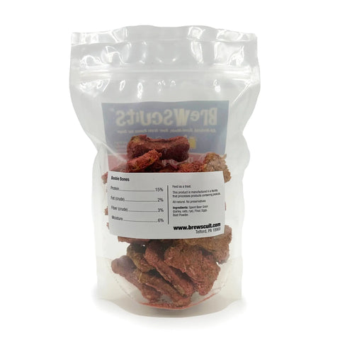 A clear resealable bag showing brown dog treats labeled Boobie Bones by Brewscuits. The white label displays nutrition facts and a website. These USA-made treats are visible through the packaging.