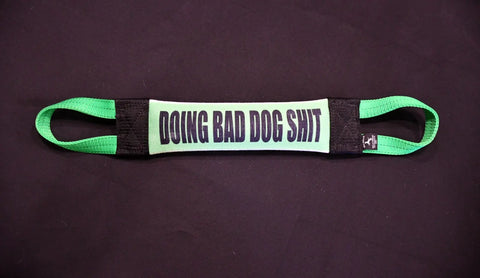 The Bulletproof Pet Products Inc Doing Bad Dog Shit Fire Hose Training Tug (Bad Tug Line) is a green and black tug toy featuring handles on both ends and the bold phrase DOING BAD DOG SHIT on a dark background.