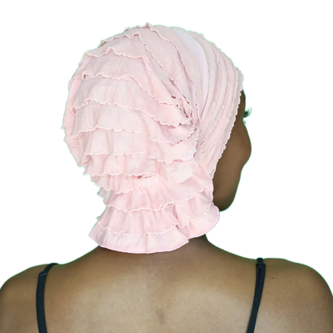 A person is seen from behind wearing a light pink Scarves - Chemo Beanies® - Donna by Chemo Beanies®, paired with a black, thin-strapped top, facing away from the camera against a plain background.