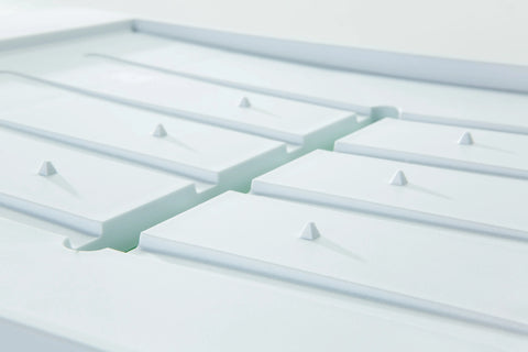 Close-up of the Karving King Dripless Cutting Board 2 in 1 System, featuring a white, geometric surface with raised rectangular panels and evenly spaced pyramid-shaped bumps for a sleek, modern look.