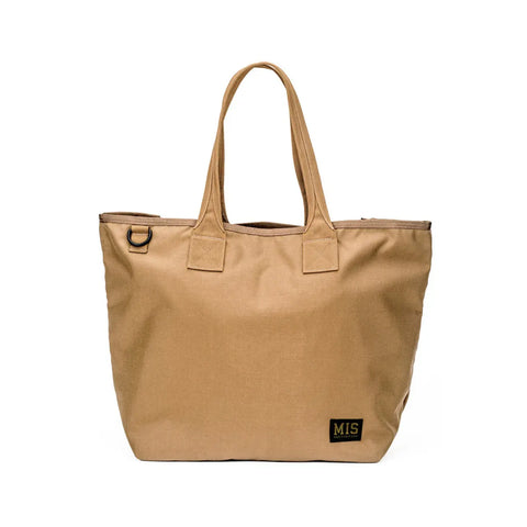The MIS Tote Bag in Coyote Brown is made of Cordura Nylon, featuring two handles, a black patch with the MIS logo on the lower right corner, and a black metal ring. Its plain, minimal design is water-resistant.