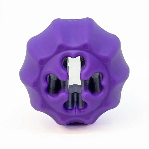The SodaPup Cross Bones Chew Toy and Treat Pocket is a purple, round rubber toy with a ridged surface and central opening for treats or chewing. Great as a treat dispenser. Shown on a plain white background.