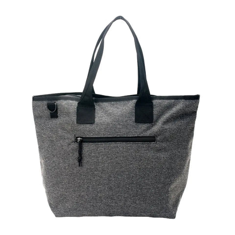 The MIS Tote Bag - Denim Grey is a large, water-resistant Cordura nylon tote with black handles, a front zippered pocket, and a small ring attachment. It features a simple, modern design for everyday use.
