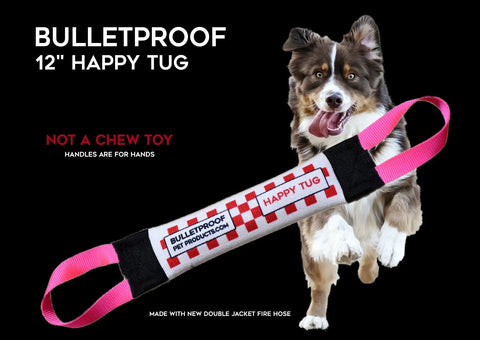 A brown and white dog runs near a Bulletproof Pet Products Inc Happy Fire Hose Training Tug—black, red, and white with pink handles. Text: BULLETPROOF 12 HAPPY TUG. Not a chew toy; handles are for hands. Perfect for play or gifts!.