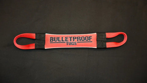 The Happy AF Fire Hose Training Tug by Bulletproof Pet Products Inc is a red and black heavy-duty dog toy with two handles and BULLETPROOF TUGS in bold black letters on a gray panel, shown against a plain black background.