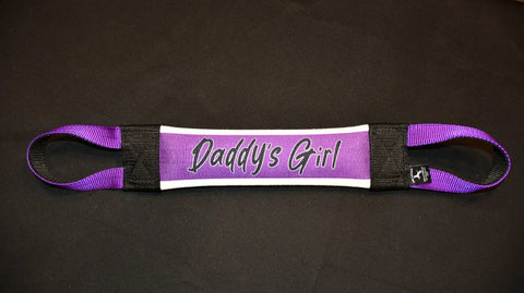 The Daddys Girl Fire Hose Training Tug by Bulletproof Pet Products Inc is a durable purple and black nylon dog toy with loops at each end and Daddys Girl in bold on the padded center, shown against a black background.