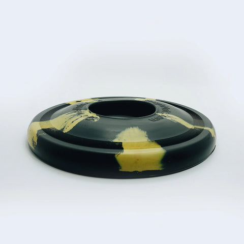 The Goughnuts Flynut, a black dog toy with yellow marbled patterns, features smooth, rounded edges and a large central hole—making it ideal for fetch games with medium dogs.