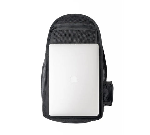 A coyote brown MIS Mesh Backpack (19L), made in the USA from durable Cordura Nylon, holds a silver Apple MacBook in its main compartment, shown from above against a white background.