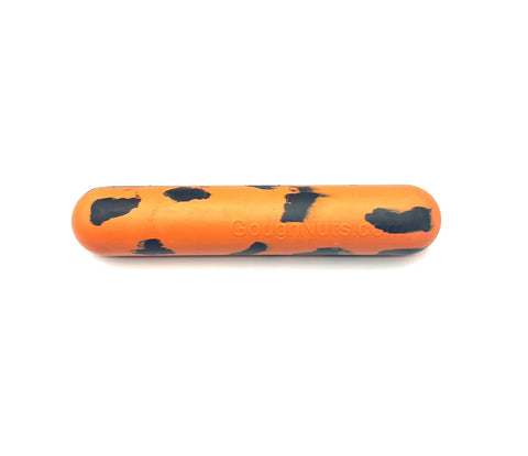 The Goughnuts Orange Stick is a durable orange cylindrical dog toy with irregular black splotches, shown on a white background.