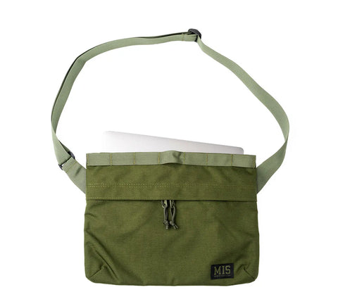 The MIS Padded Shoulder Bag - Olive Drab is a water-resistant Cordura nylon laptop bag with a wide strap, zippered front pocket, and a small black MIS patch. Made in the USA, it’s shown partially open to reveal a silver laptop inside.
