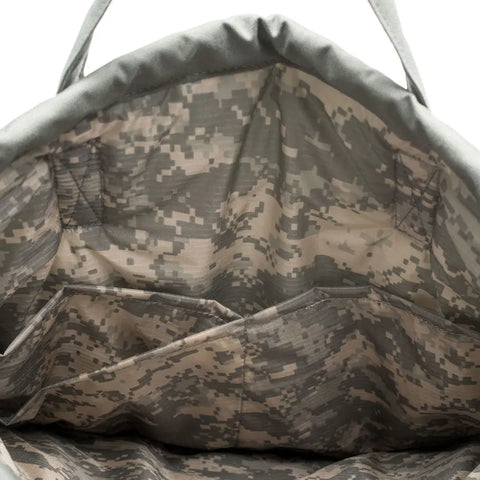 The image shows the interior of the MIS UK Helmet Bag - Foliage, made from Cordura Nylon. The lining features a digital camouflage pattern in green, beige, and brown with multiple compartments for organization.