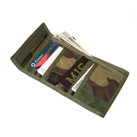 The MIS Folding Wallet - Woodland Camo, made in the USA, opens to display cash, credit cards, an ID, and other cards neatly organized in clear slots.
