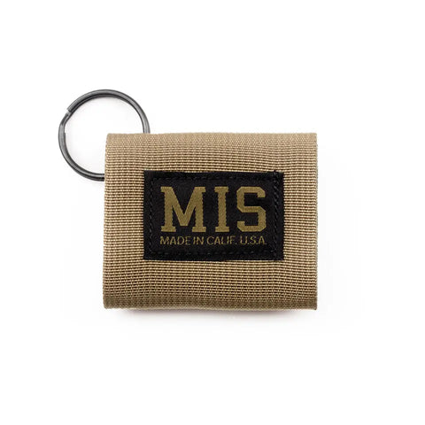 The MIS Duty Key Silencer in coyote tan is made from heavy-duty nylon webbing with a black key ring. A front black patch with yellow MIS MADE IN CALIF. U.S.A. text highlights its quality, American-made craftsmanship.