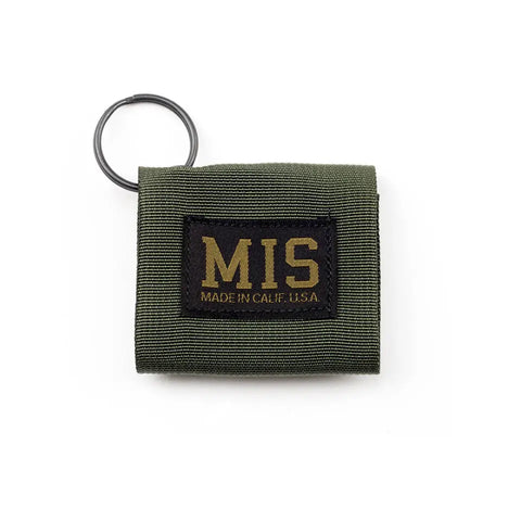The MIS Duty Key Silencer in Olive Drab is a compact USA-made fabric pouch with a black keyring, black patch labeled “MIS MADE IN CALIF. U.S.A.” in yellow, and a Velcro closure for secure, convenient storage.