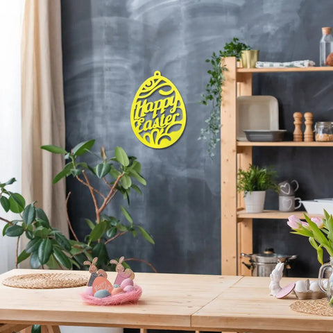 A cozy dining area features a wooden table with Easter décor, a plant, a blackboard wall adorned with the Chatelet Manufacturing FRESHe Easter Wall Hanger, and wooden shelves displaying dishes, plants, and kitchen items.