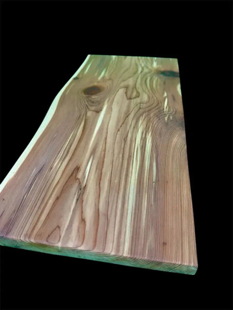 A close-up of the Eastern Red Cedar Live Edge Charcuterie Board by B. James Design & Woodwork, showcasing its handcrafted quality, natural grain patterns, and knots against a solid black background.