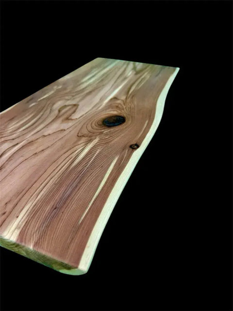 The Eastern Red Cedar Live Edge Charcuterie Board by B. James Design & Woodwork, featuring natural grain patterns and knots, is displayed against a solid black background.