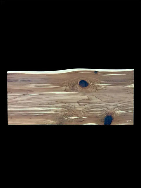 The Eastern Red Cedar Live Edge Charcuterie Board by B. James Design & Woodwork features a rectangular, handcrafted plank with visible knots and grain on natural wood, set against a solid black background.