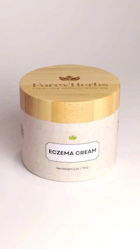 A jar with a wooden lid labeled Eczema Cream and Forev'Herbs sits on a white surface. This off-white, round container features natural skincare for sensitive skin and displays a net weight of 4 oz (113 g).