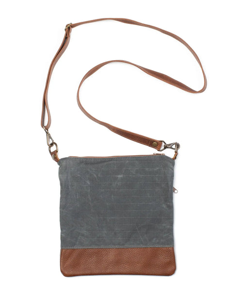 The Rogue Industries Ellis River Crossbody Bag, shown on a white background, features a blue-gray waxed canvas body, brown leather bottom, and a long brown leather strap.