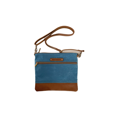 The Ellis River Crossbody Bag by Rogue Industries is a blue leather and waxed canvas purse with a brown adjustable strap, leather bottom, front zipper pocket, and a small leather brand patch near the top.