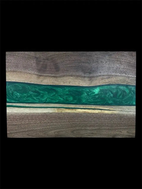 The B. James Design & Woodwork Emerald Green Epoxy and Walnut Serving Board is handcrafted in the USA with a central emerald green epoxy strip between two walnut slabs, all set against a black background.