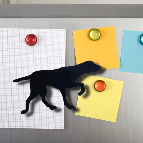 The Chatelet Manufacturing English Pointer Dog Fridge Magnet in black holds graph paper on a silver fridge, while colorful magnets secure sticky notes—a perfect gift for dog lovers.