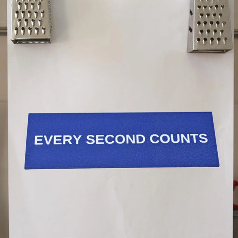 The Every Second Counts Fridge Magnet by Chatelet Manufacturing is a blue rectangle with white text and two metal accents at the top, highlighting American craftsmanship against a white background.