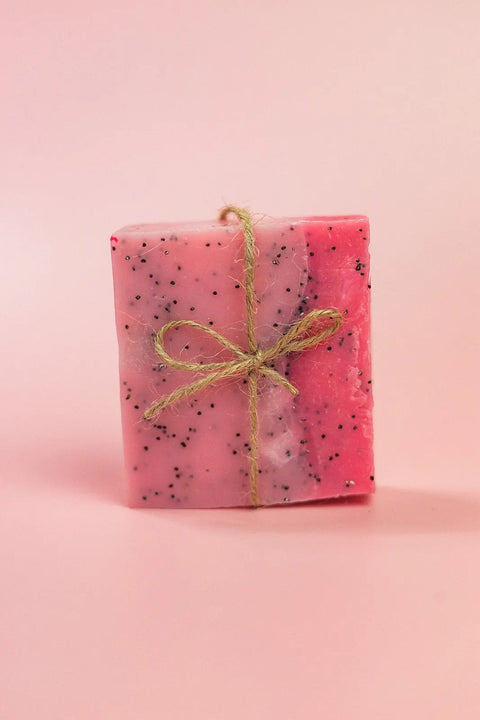 The Shanti + Tula Exfoliating Goat’s Milk Soap Bar with Pumice, handcrafted in Utah, sits against a light pink background—an exfoliating and moisturizing treat for your daily routine.