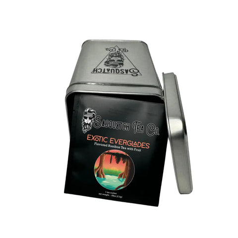 An open Sasquatch Tea Co. metal tin reveals the Exotic Everglades Rooibos Fruit Tea, featuring a front label with an illustrated forest scene inspired by Everglades National Park.