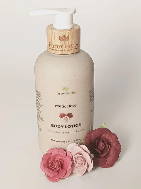 A Forev'Herbs Exotic Rose Lotion with a wooden pump sits beside three artificial roses—one pink and two deep red—on a white background.