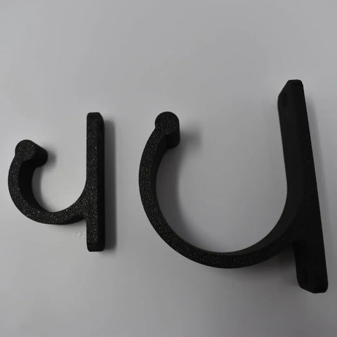 Two black, U-shaped FRESHe Horizontal Fishing Rod Holders by Chatelet Manufacturing, in different sizes, are displayed on a white surface. Each bracket features a flat base with two mounting holes for easy fishing rod storage.