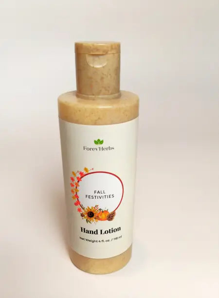 A bottle of Forev'Herbs Fall Festivities Hand Lotion with a white label displaying autumn leaves, sunflowers, and a pumpkin. The light brown lotion inside contains visible specks.