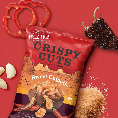 A 1oz bag from Field Trip’s Sweet Chipotle 6 Pack—gluten free and keto friendly—is showcased with red pepper, dried chili, garlic cloves, and brown sugar on red, emphasizing its bold chipotle heat.